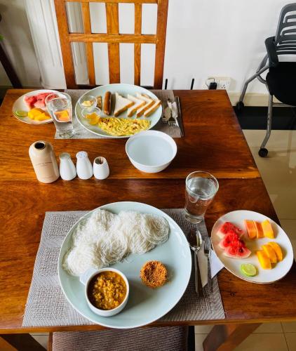 a wooden table with plates of food on it at Lavinia Blue Hotel in Mount Lavinia