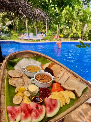 a tray of food on a table next to a pool at Sundaras Sigiriya Jungles Caves Resort in Dambulla