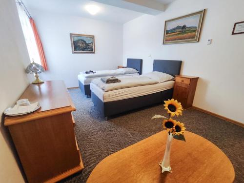 a room with a bed and a table with a vase with a sunflower at Restaurace Penzion Na Poště in Strašice