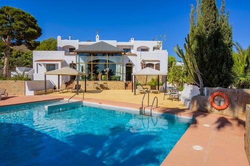 a villa with a swimming pool in front of a house at Family Agua Amarga in Agua Amarga