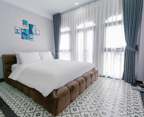 a bedroom with a large bed in front of windows at Cosy Hotel in Ho Chi Minh City