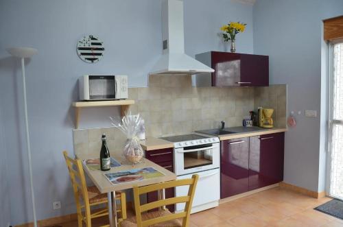 a kitchen with a table with chairs and a microwave at Maison charmante à Botsorhel avec jardin clôturé de 31 m² in Botsorhel