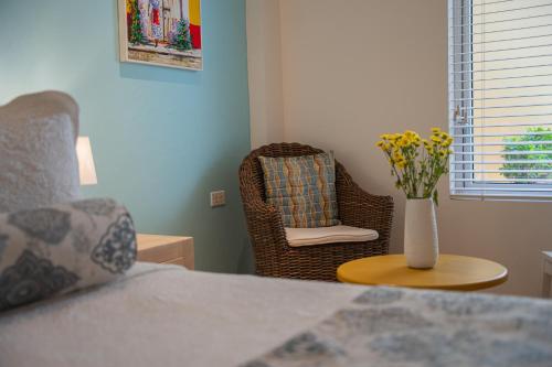 a bedroom with a chair and a vase of flowers on a table at Posada La Fe in Cartagena de Indias