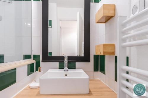 une salle de bain avec un lavabo blanc et un miroir dans l'établissement Les Pins dorés le petit nid douillet et cosy, à Soustons