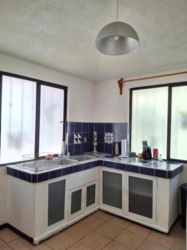 a kitchen with blue tiled counters and windows at habitación en medio de la naturaleza in Zacatlán