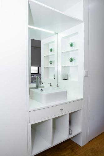 a white bathroom with a sink and a mirror at Póvoa Beach Apartment in Póvoa de Varzim