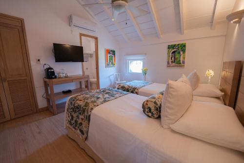 a hotel room with two beds and a television at Posada La Fe in Cartagena de Indias