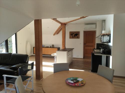 a living room with a table and a kitchen at Appartement au calme, dans résidence sécurisée avec place de stationnement in Saint-Georges-de-Commiers