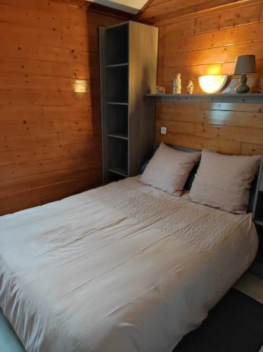 - une chambre avec un lit blanc et un mur en bois dans l'établissement Chalet 31, à Le Mas