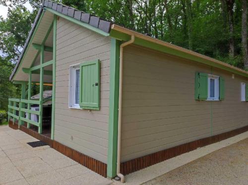 - un petit bâtiment avec des fenêtres vertes et une terrasse couverte dans l'établissement Chalet 31, à Le Mas