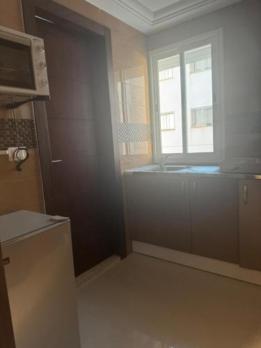 een keuken met een spoelbak en een raam bij Les portes délavées in Sfax