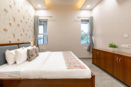 a bedroom with a large bed and two windows at ELIVAAS Jamun Farm 2BHK with Pool in Jaipur