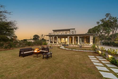 a house with a fire pit in the yard at ELIVAAS Jamun Farm 2BHK with Pool in Jaipur