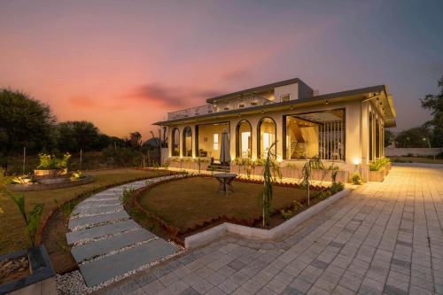 a house with a patio and a garden at night at ELIVAAS Jamun Farm 2BHK with Pool in Jaipur