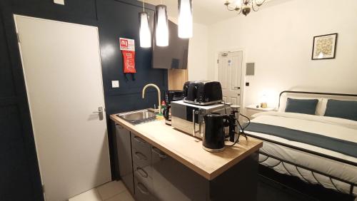 a kitchen with a sink and a room with a bed at Fulforth St Studio Apartments in Nottingham