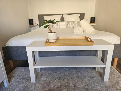 une table blanche avec une plante à côté d'un lit dans l'établissement 2 pièces lumineux, proche plage, parking, clim, hippodrome, à Cagnes-sur-Mer