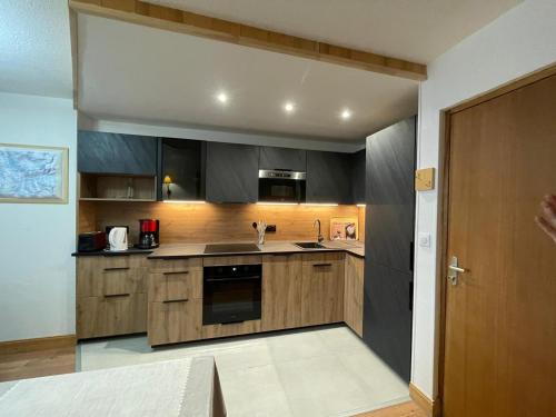 une cuisine avec des armoires en bois et des appareils en acier inoxydable dans l'établissement Appartement rénové 2 pièces au pied des pistes - Exposé Sud-Ouest, balcon, animaux OK - FR-1-449-10, à Tignes