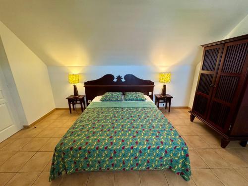 a bedroom with a bed with a green comforter at Kaz Caraïbes spacieuse, accès piscine et plage - Résidence in Sainte-Luce
