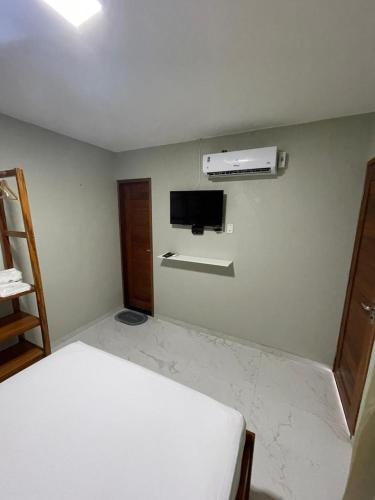 a room with a bed and a tv on a wall at Suítes Paraíso Perfeito in Flecheiras