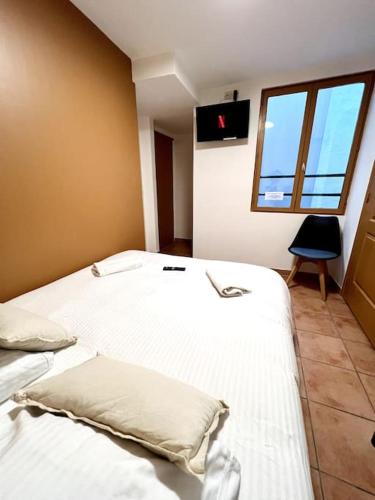 une chambre avec un lit avec des draps blancs et une fenêtre dans l'établissement Les chambres de la bastide - 201, à Carcassonne