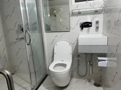 a white bathroom with a toilet and a shower at Rumi HomeStays in Bhubaneshwar