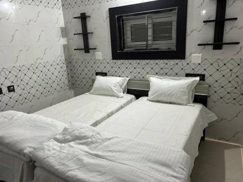 two beds with white sheets in a room with a window at Rumi HomeStays in Bhubaneshwar