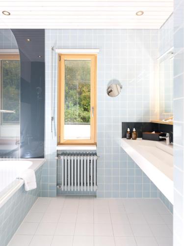 a blue tiled bathroom with a window and a tub at Beausite Park Hotel & Spa in Wengen