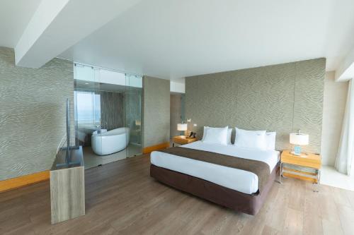 a bedroom with a large bed and a bathroom at Terrado Suites Antofagasta in Antofagasta