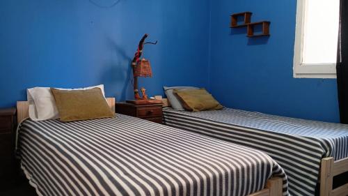 two beds in a room with blue walls at Casita del Centro in San Clemente del Tuyú