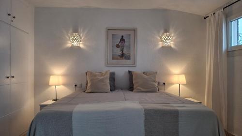 een witte slaapkamer met een bed met 2 lampen bij Carmen Casa Helena in Nerja