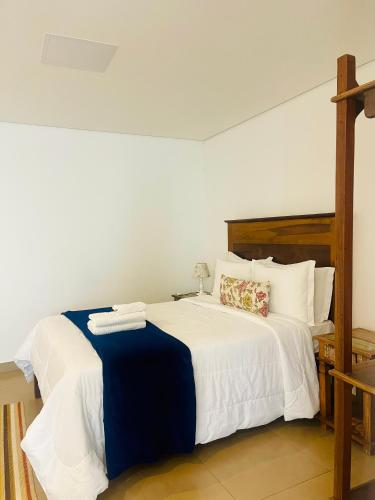 a bedroom with a bed with white sheets and pillows at Pousada Villa Tiradentes Suítes - Centro in Tiradentes