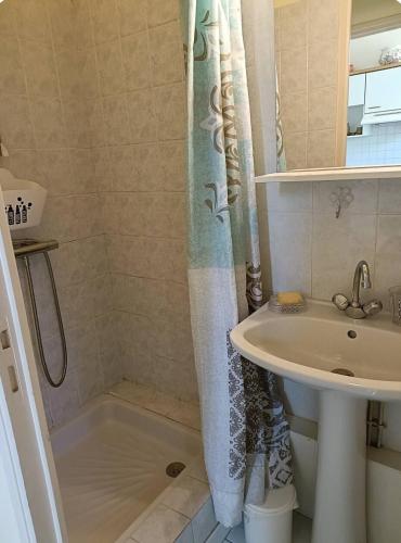 une salle de bain avec un rideau de douche et un lavabo dans l'établissement Maison près de la Rance dans un village, à Taden