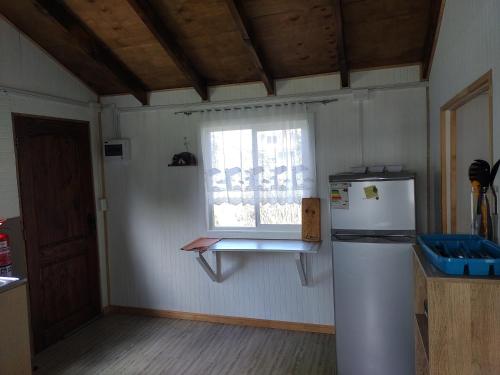 a kitchen with a refrigerator and a window at Cabaña Ruta Petrohue in Ensenada