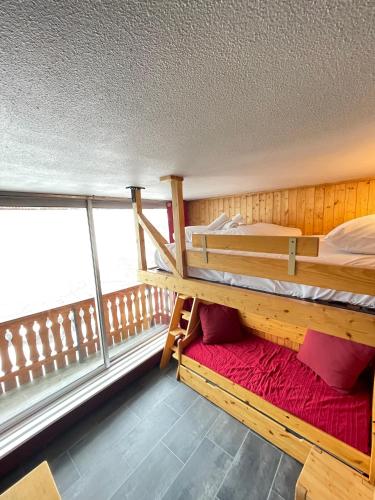 a room with two bunk beds and a balcony at Dome De Polset Condo by AlpStays in Val Thorens