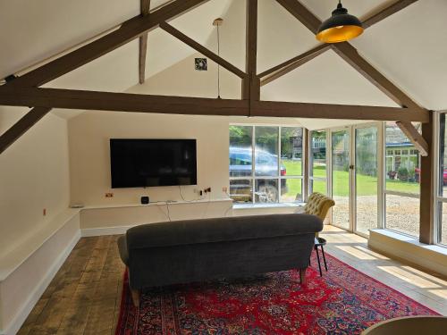 ein Wohnzimmer mit Couch und Flachbildfernseher in der Unterkunft The Old Stables - Self Contained Cottage - Hot Tub and Pool in Salisbury