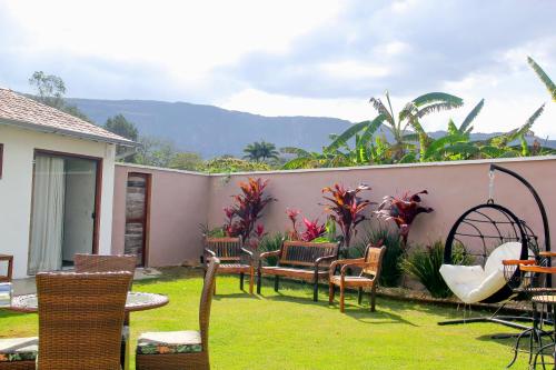 a patio with chairs and tables in a yard at Pousada Villa Tiradentes Suítes - Centro in Tiradentes