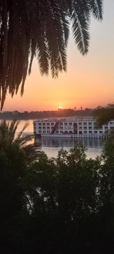 a building on the water with the sunset in the background at Villa Rose-Luxor in Luxor