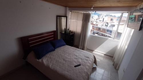 a bedroom with a bed with blue pillows and a window at apartamento Emanuel in Duitama