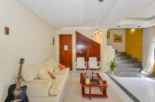 a living room with a white couch and a guitar at Casa do Loro Hospedagem in Curitiba
