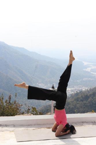 a woman doing a handstand on top of a mountain at The Sweven NeerVan in Rishīkesh