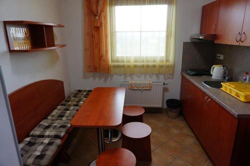 a small kitchen with a wooden table and stools at Penzion Martin in Janske Lazne