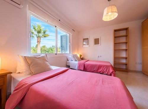 two beds in a room with a palm tree in the window at Villa Can Petrus, con piscina y wifi gratis in San Antonio Bay