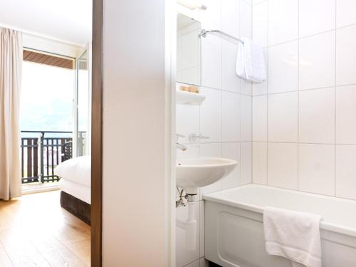 a white bathroom with a tub and a sink at Beausite Park Hotel & Spa in Wengen