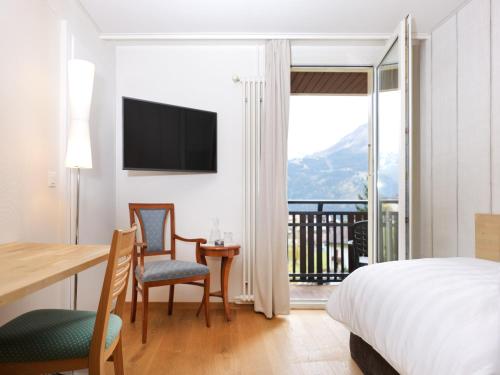 a hotel room with a bed and a table and chairs at Beausite Park Hotel & Spa in Wengen