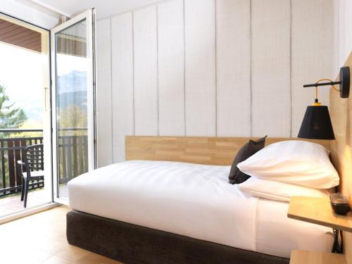 a bedroom with a bed and a balcony at Beausite Park Hotel & Spa in Wengen