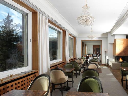 a dining room with chairs and tables and windows at Beausite Park Hotel & Spa in Wengen