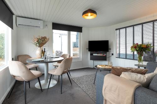 a living room with a table and chairs and a tv at Woonboot De Rietpieper in Loosdrecht