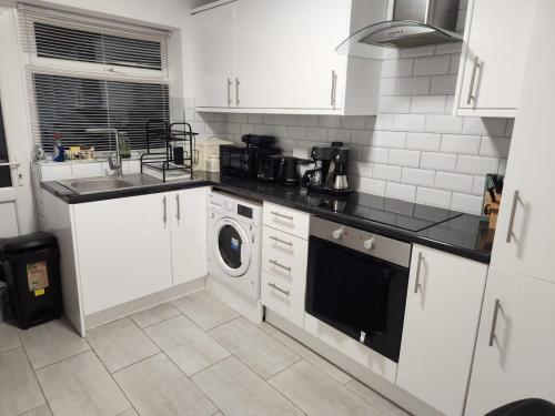 a kitchen with white cabinets and a washer and dryer at Dmltd in Northampton