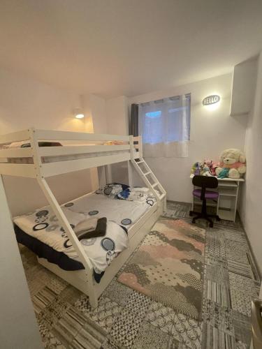 Cette petite chambre comprend des lits superposés et un bureau. dans l'établissement Appartement proche centre Colmar parking public gratuit, à Colmar