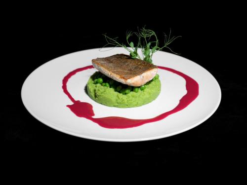 a plate of food with a piece of meat on a green sauce at Beausite Park Hotel & Spa in Wengen